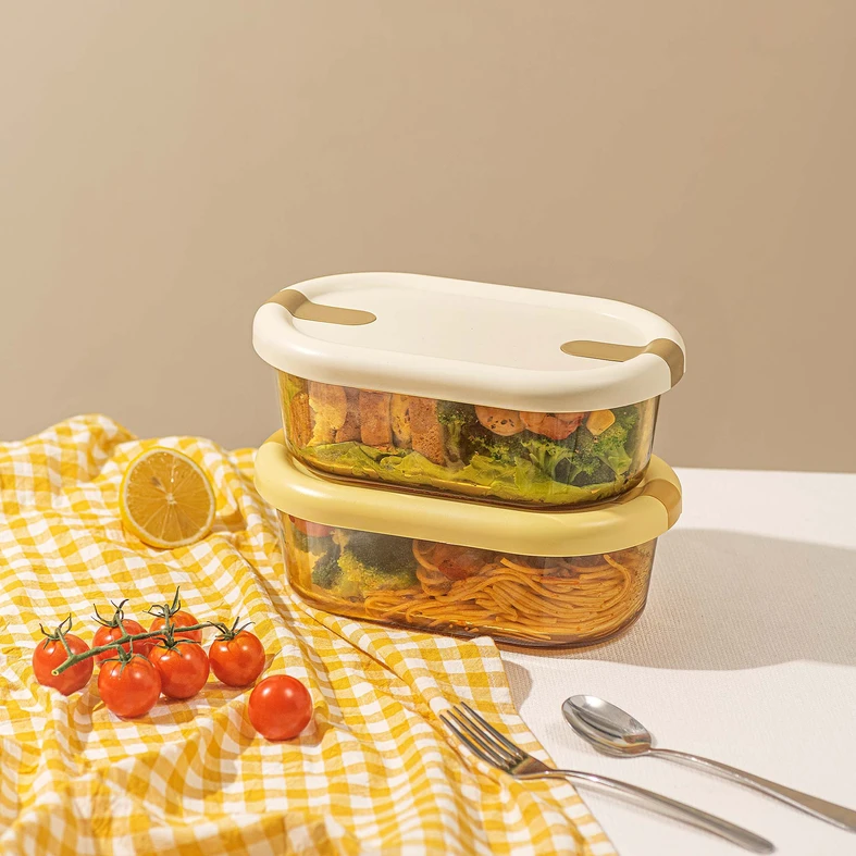 Dwa szklane pojemniki na żywność, jeden na drugim. W jednym makaron z warzywami, w drugim kanapki i krewetki z warzywami.