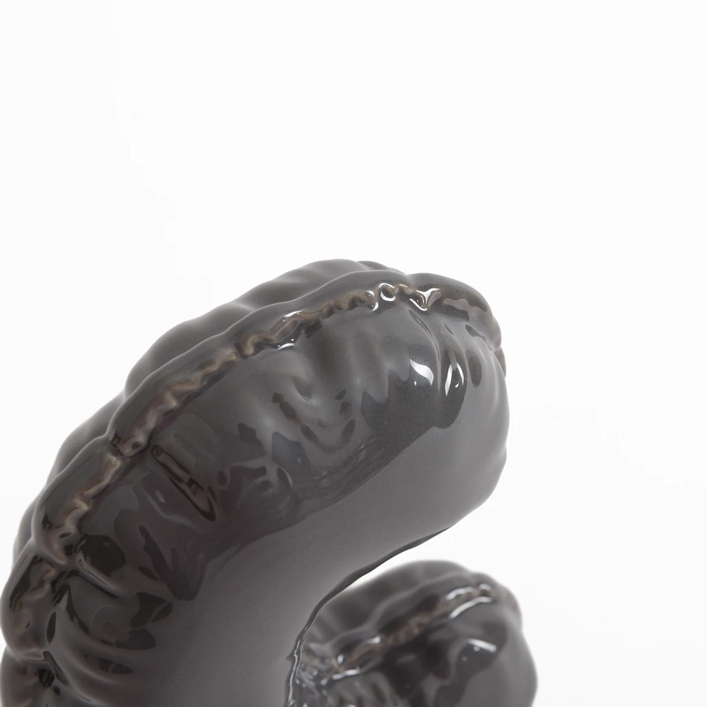 Szara figurka dekoracyjna w kształcie litery C.