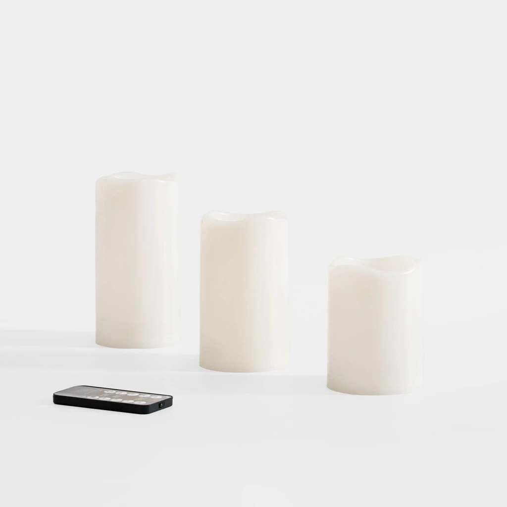 Trzy świece różnej wysokości w kolorze złamanej bieli i pilot w zestawie.