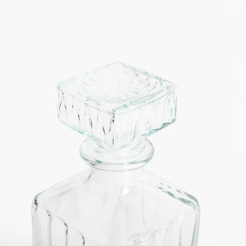 Zbliżenie na wierzchołek karafki z jej korkiem, wykonane z przejrzystego szkła.