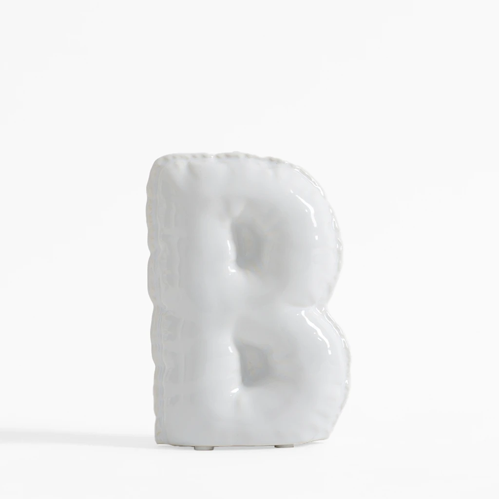 Biała figurka dekoracyjna w kształcie litery B.