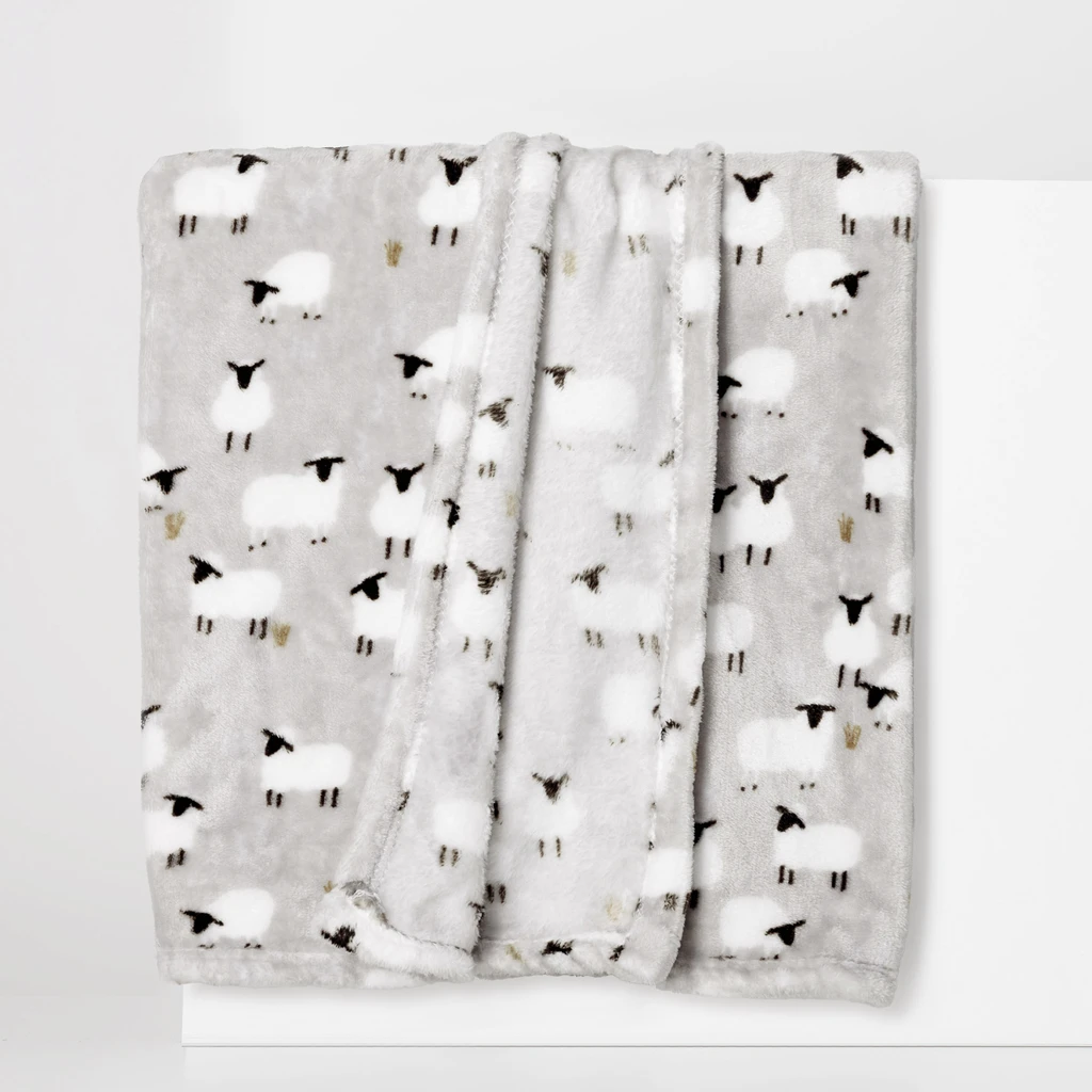 Mięciutki szary koc w owieczki z białym futerkiem oraz czarnymi głowami i nóżkami.