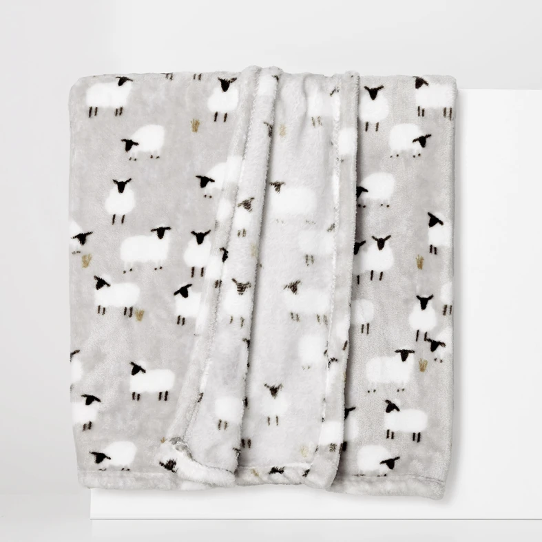 Mięciutki szary koc w owieczki z białym futerkiem oraz czarnymi głowami i nóżkami.