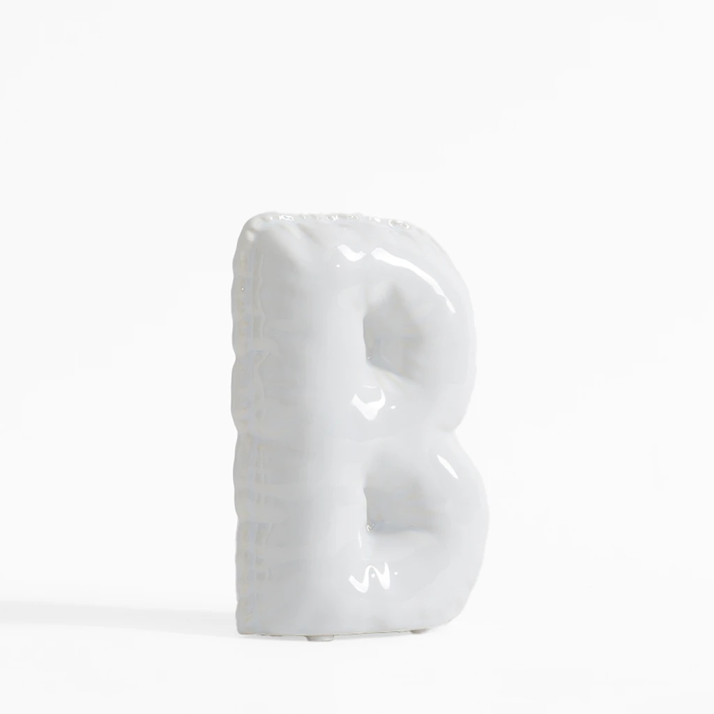 Biała figurka dekoracyjna w kształcie litery B.