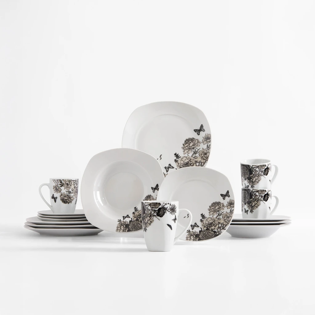 Zestaw obiadowy z delikatnym kwiatowym wzorem na białej porcelanie. Rysunek kwiatów piwonii i wirujących wokół nich motyli, uzupełniony kolorem jasnej sepii. Widoczne talerze obiadowe, głębokie i deserowe oraz kubki.