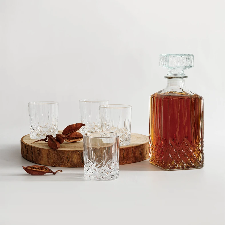 Aranżacja, część zestawu stoi na ozdobnym krążku z pnia drzewa. W karafce bursztynowy napój. 