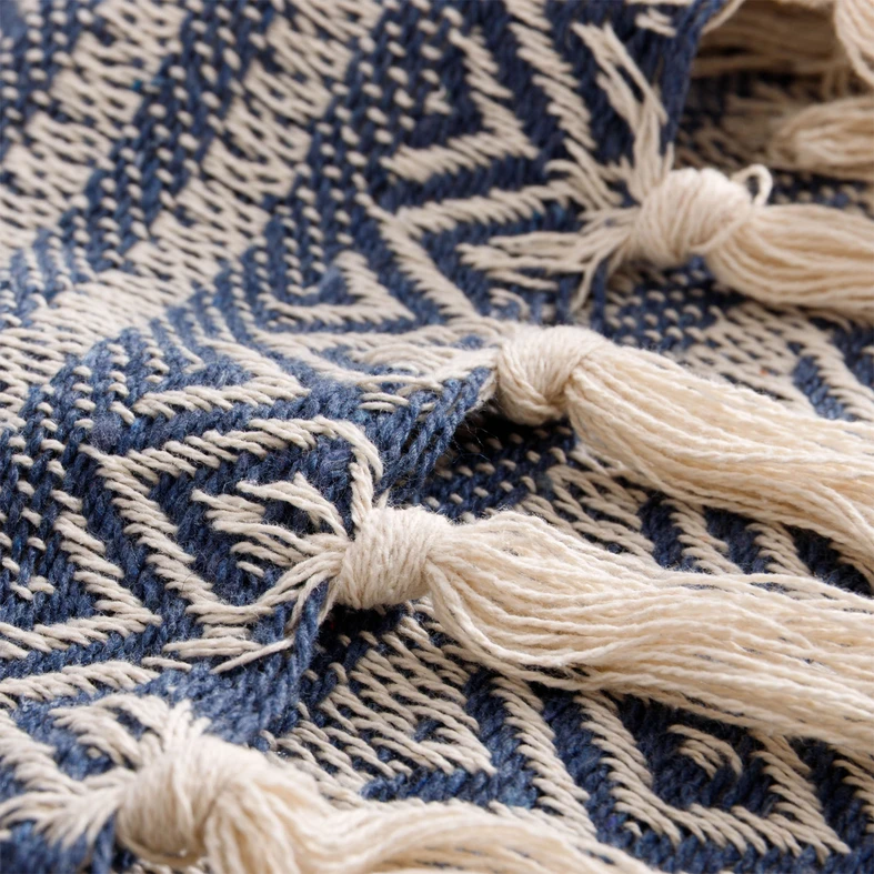 Detal, kremowe frędzle ułożone na tle splotu.