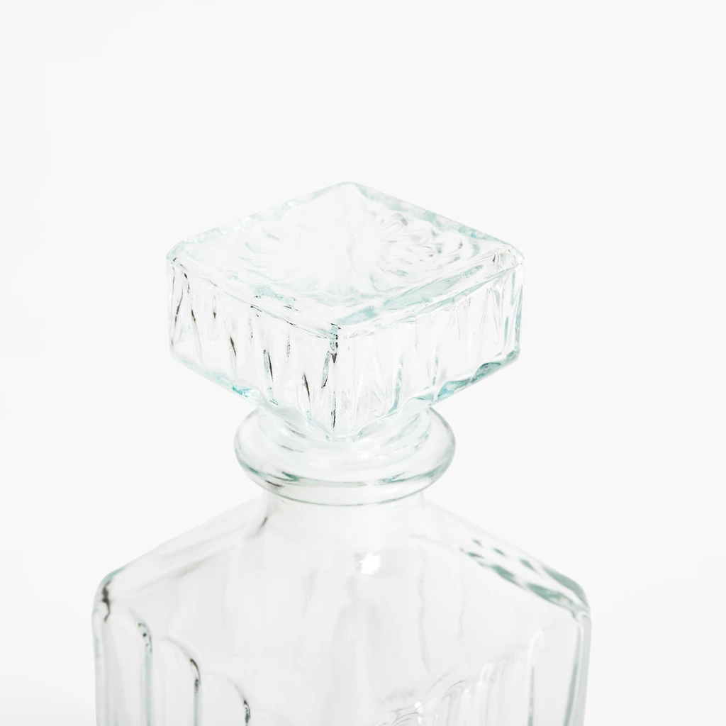 Zbliżenie na wierzchołek karafki z jej korkiem, wykonane z przejrzystego szkła.