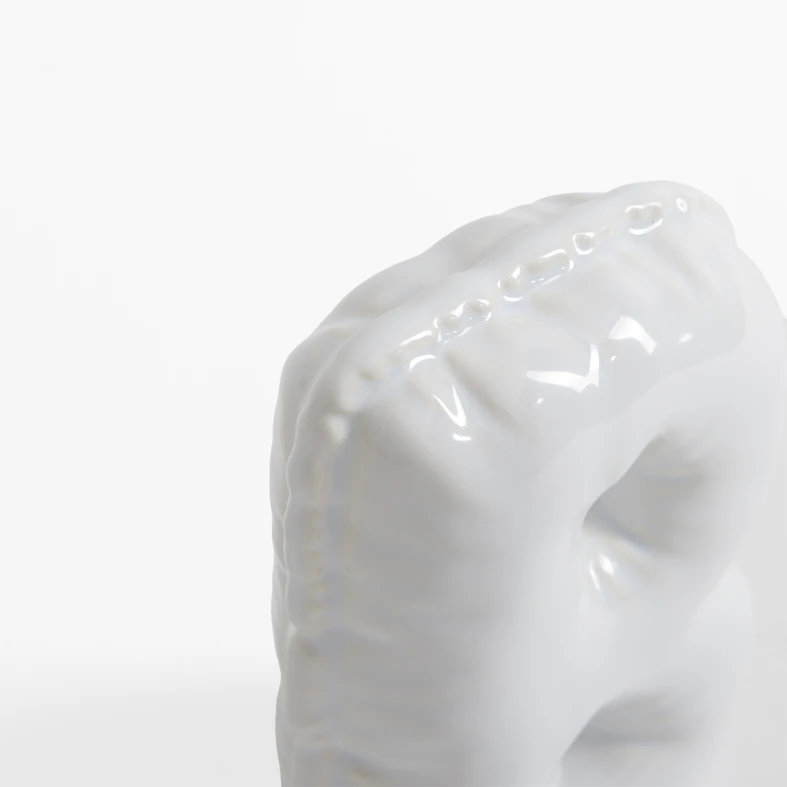 Biała figurka dekoracyjna w kształcie litery B.