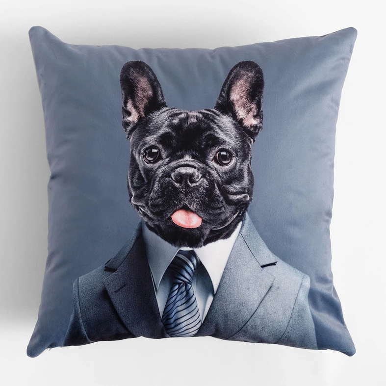 Poduszka z motywem psa w garniturze, z tyłu bez wzoru, w dotyku przypominająca welur, elegancka i nieco surrealistyczna.