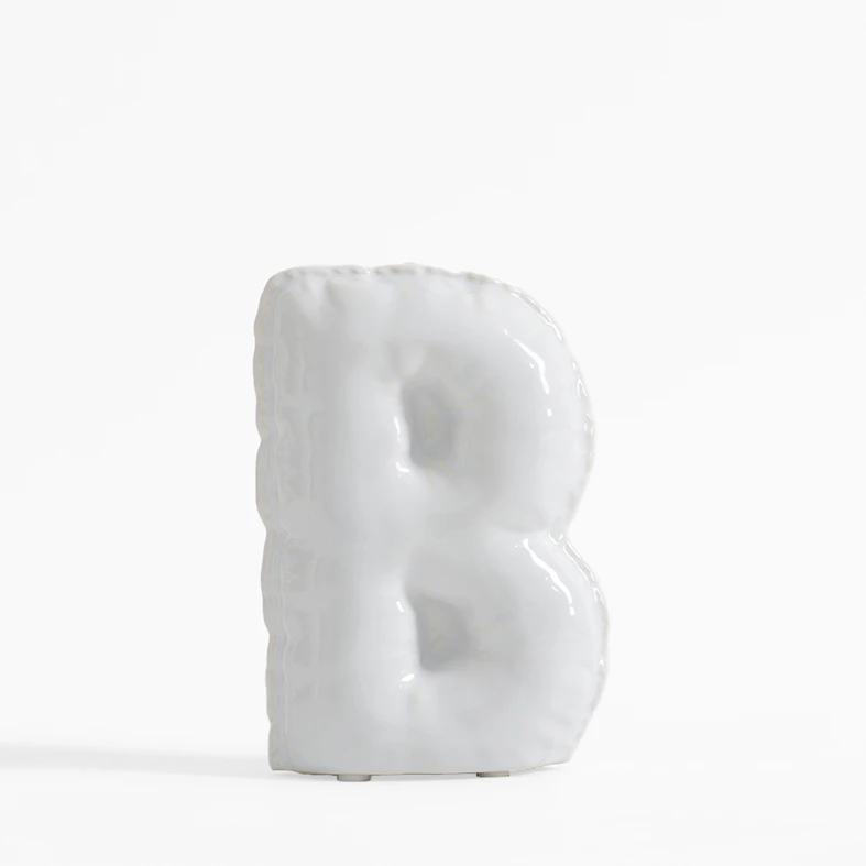 Biała figurka dekoracyjna w kształcie litery B.