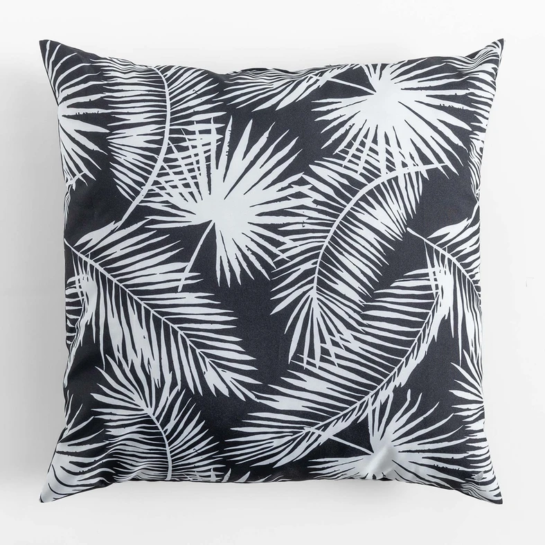 Kwadratowa, puchata poduszka dekoracyjna do ogrodu, o wzorze białych liści palmowych na czarnym tle, o gładkim, czarnym tyle.
