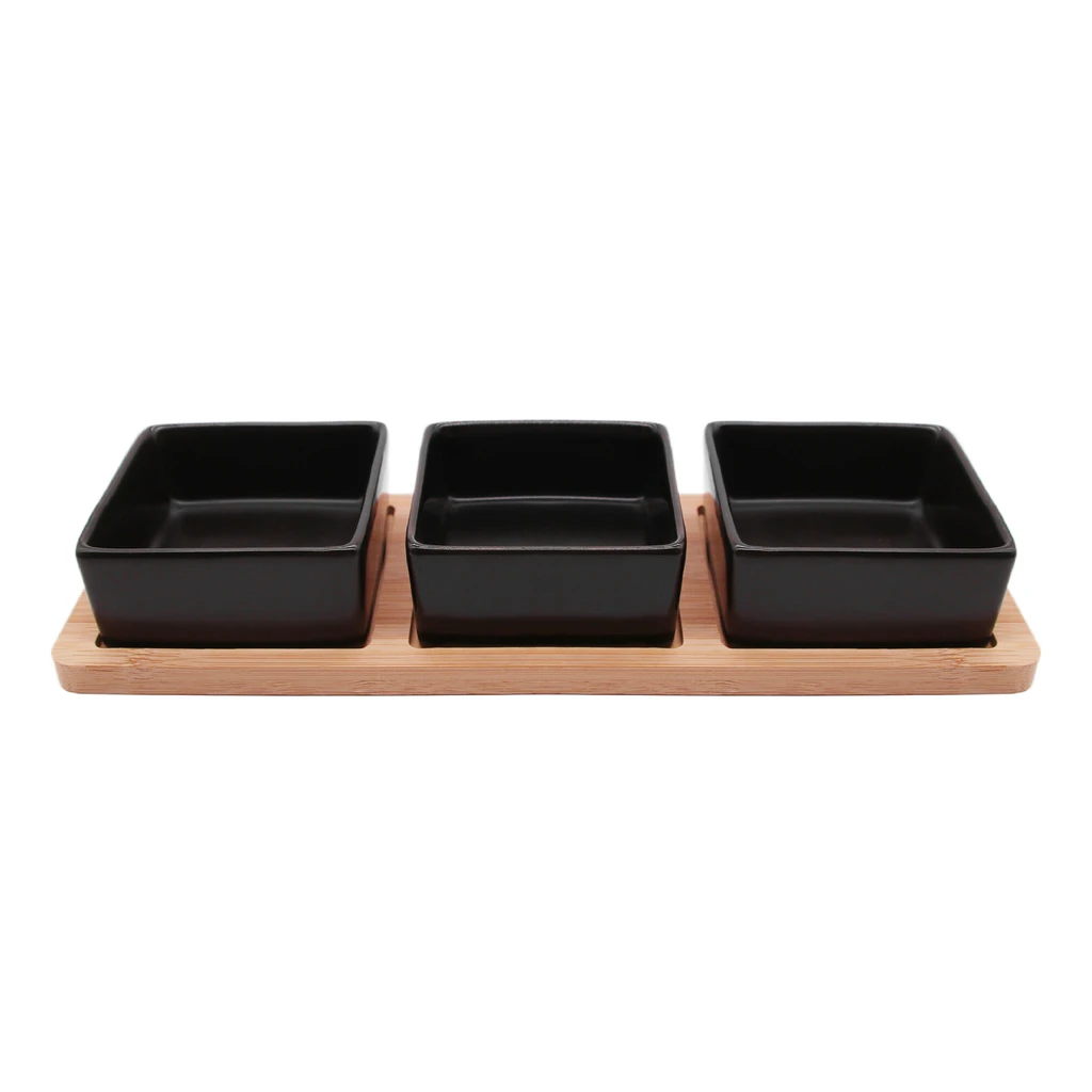 Trzy czarne kwadratowe miski z kamionki na bambusowej podstawie