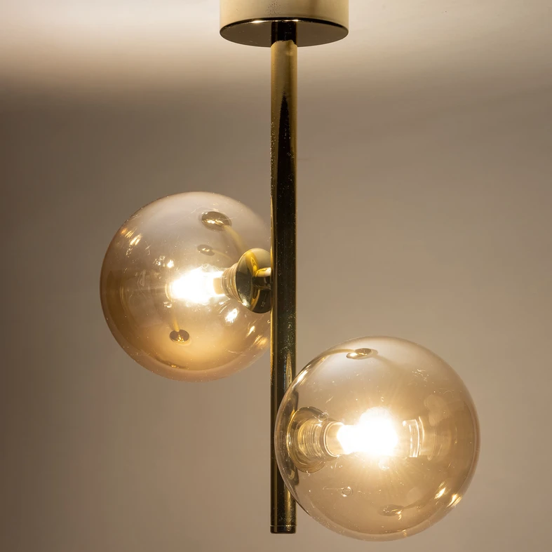 Żarówki osłaniają kuliste, transparentne klosze o bursztynowym zabarwieniu.