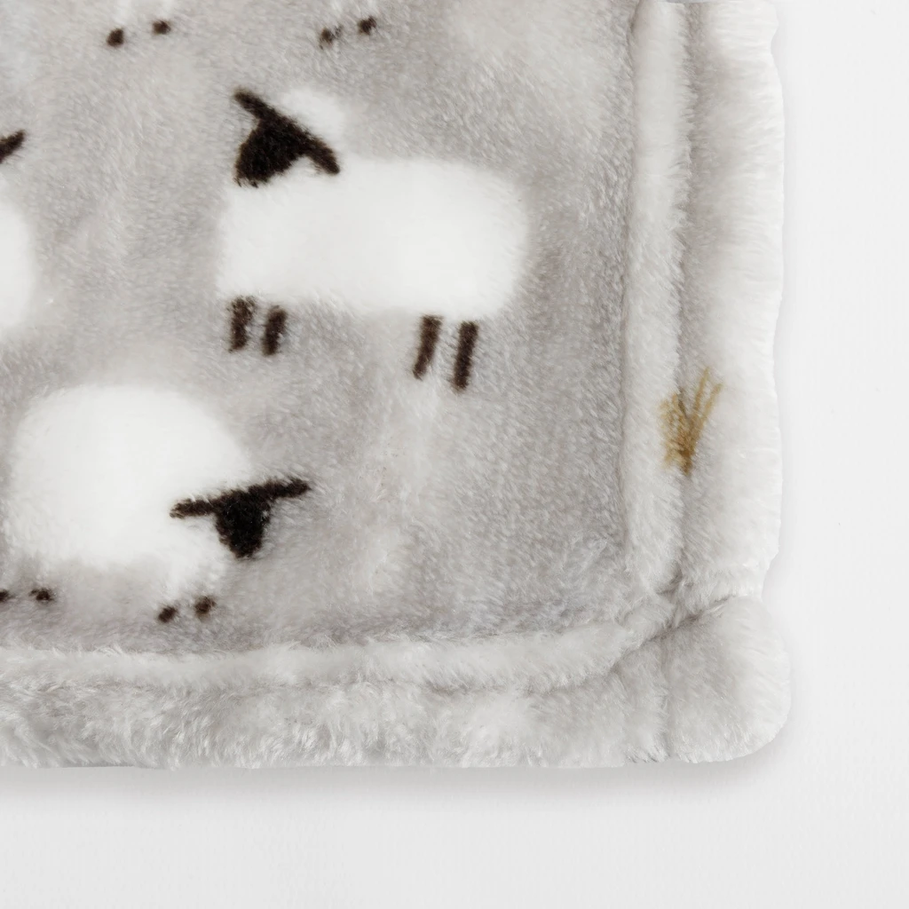 Detal, staranne wykończenie krawędzi koca z owieczkami.