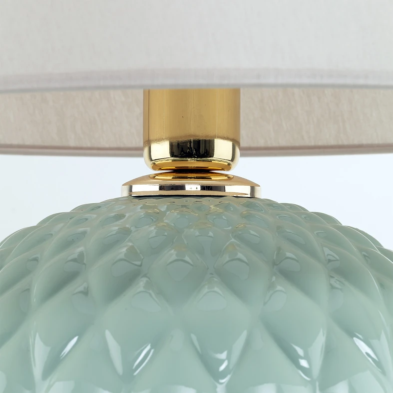 SANTANA wykonana została ze szkła z podstawą w odcieniu mięty i złotym wykończeniem przy oprawie żarówki.