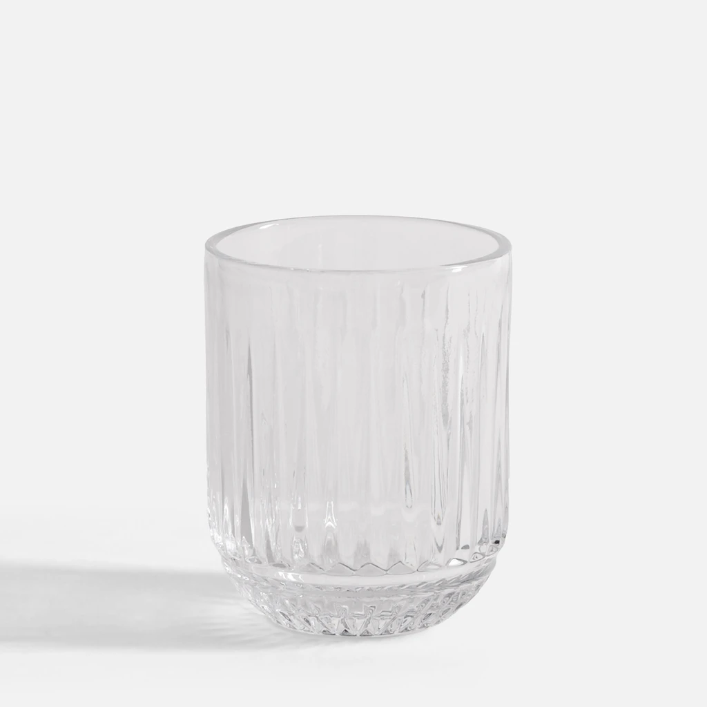 Niska szklanka z przejrzystego szkła, o pionowych żłobieniach i drobnych tłoczeniach w podstawie.