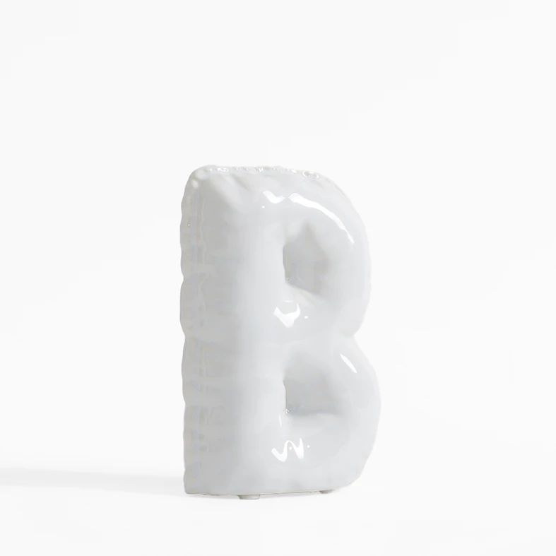 Biała figurka dekoracyjna w kształcie litery B.