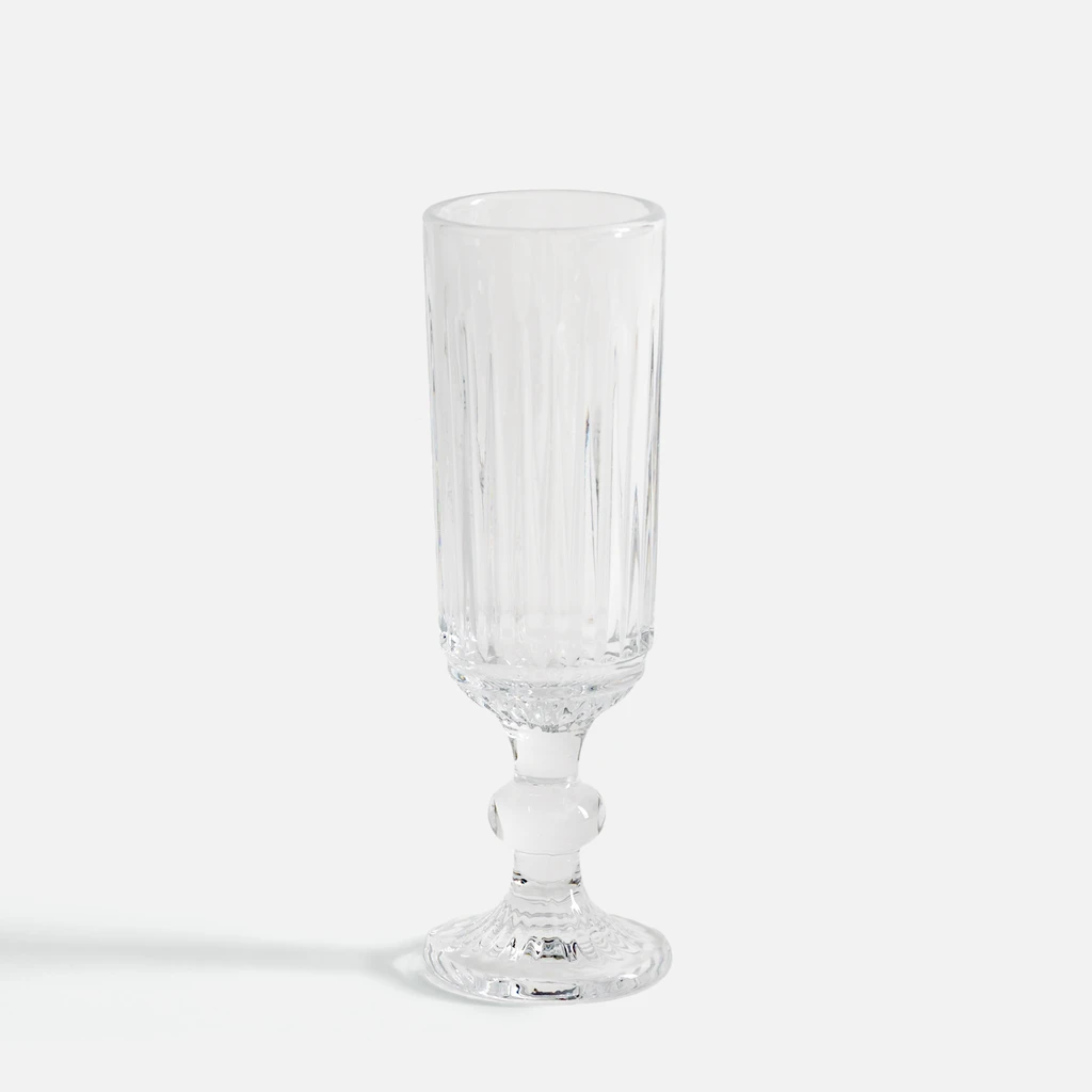 Elegancki, smukły kieliszek do szampana, o pionowych żłobieniach, na dekoracyjnej nóżce.