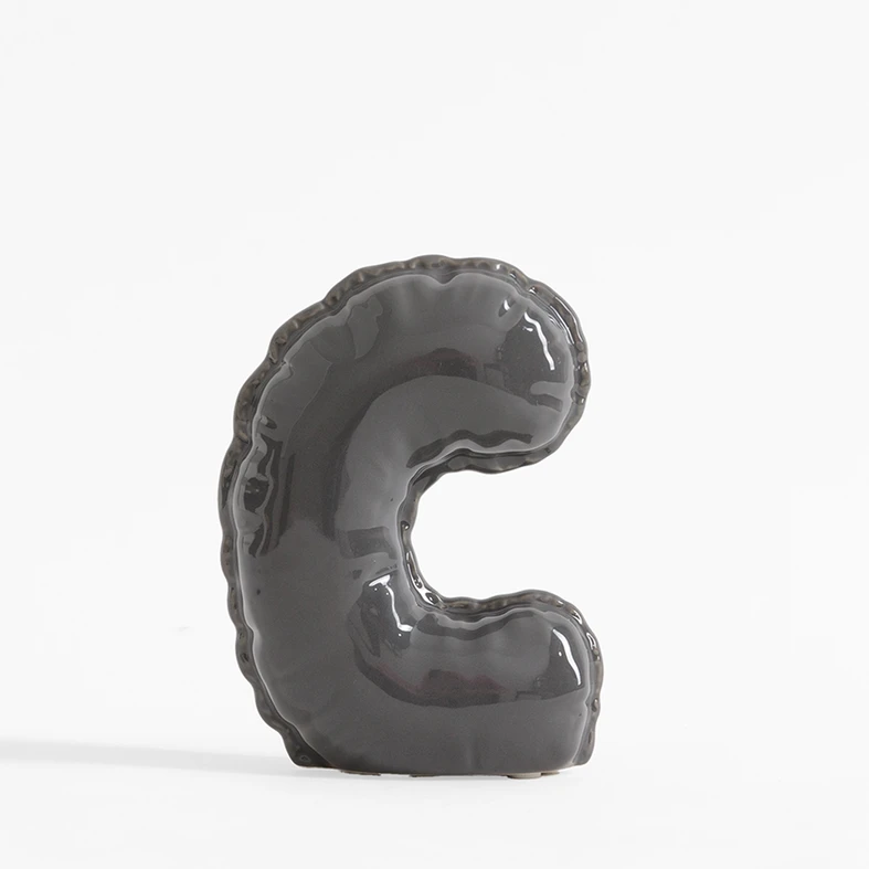 Szara figurka dekoracyjna w kształcie litery C.