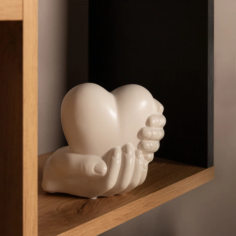 Biała dekoracja w kształcie dłoni trzymających serce.