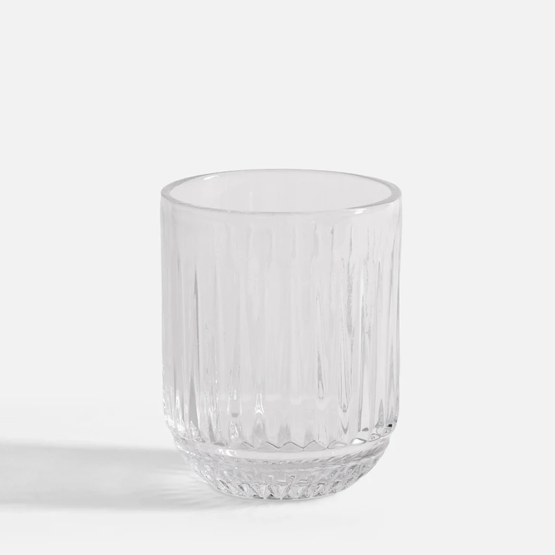Niska szklanka z przejrzystego szkła, o pionowych żłobieniach i drobnych tłoczeniach w podstawie.