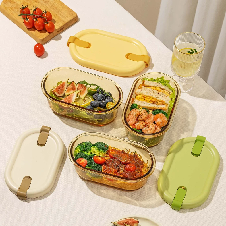 Trzy owalne lunchboxy, w jednym sałatka z figami, w drugim kanapki i krewetki, w trzecim makaron z sosem. 