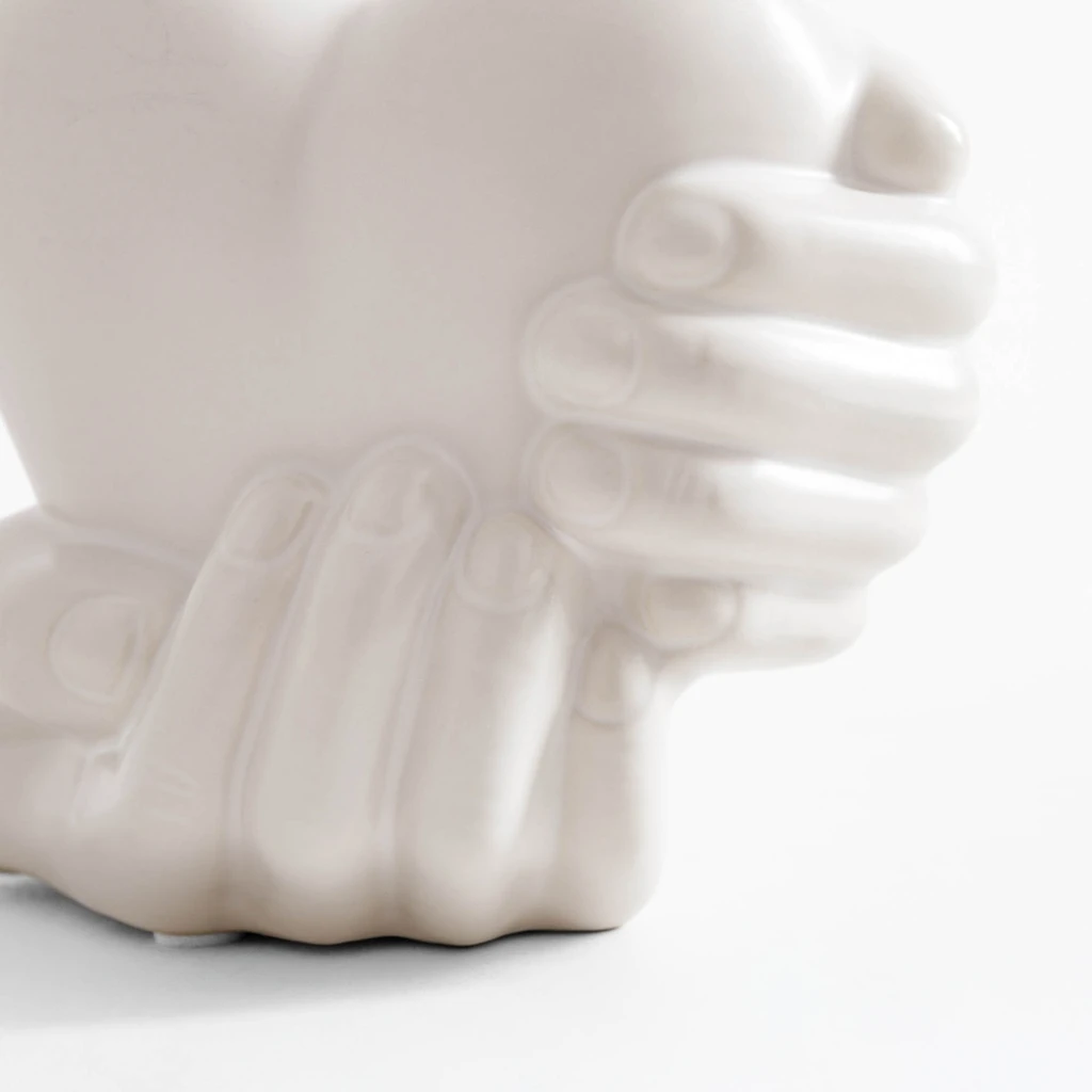 Biała dekoracja w kształcie dłoni trzymających serce.