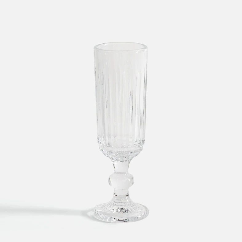 Elegancki, smukły kieliszek do szampana, o pionowych żłobieniach, na dekoracyjnej nóżce.