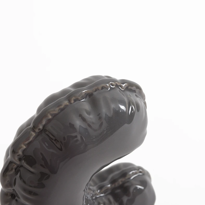 Szara figurka dekoracyjna w kształcie litery C.